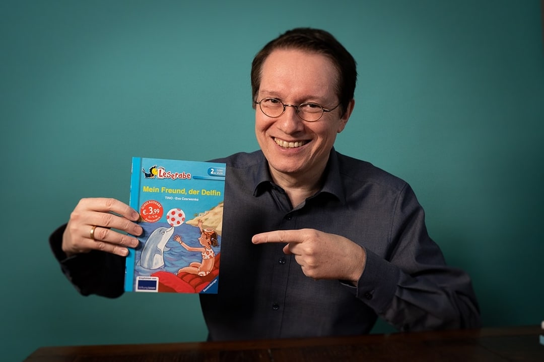 TINO hält ein Buch in der Hand